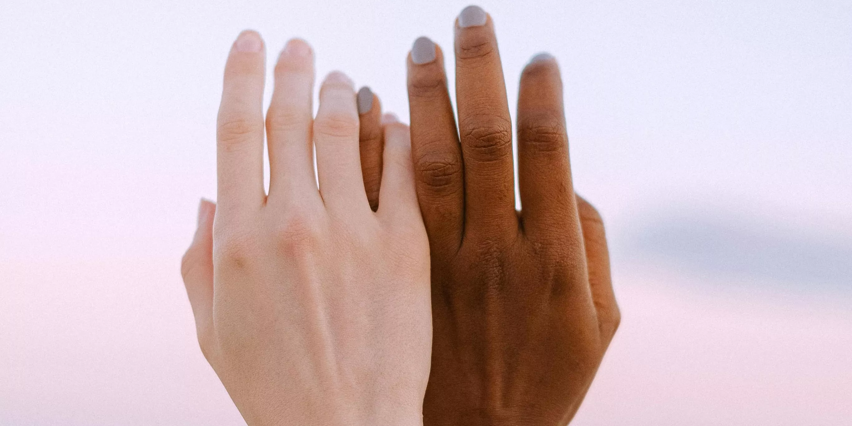 Dues mans, una duna persona de color i una altra duna persona blanca, aixecades.