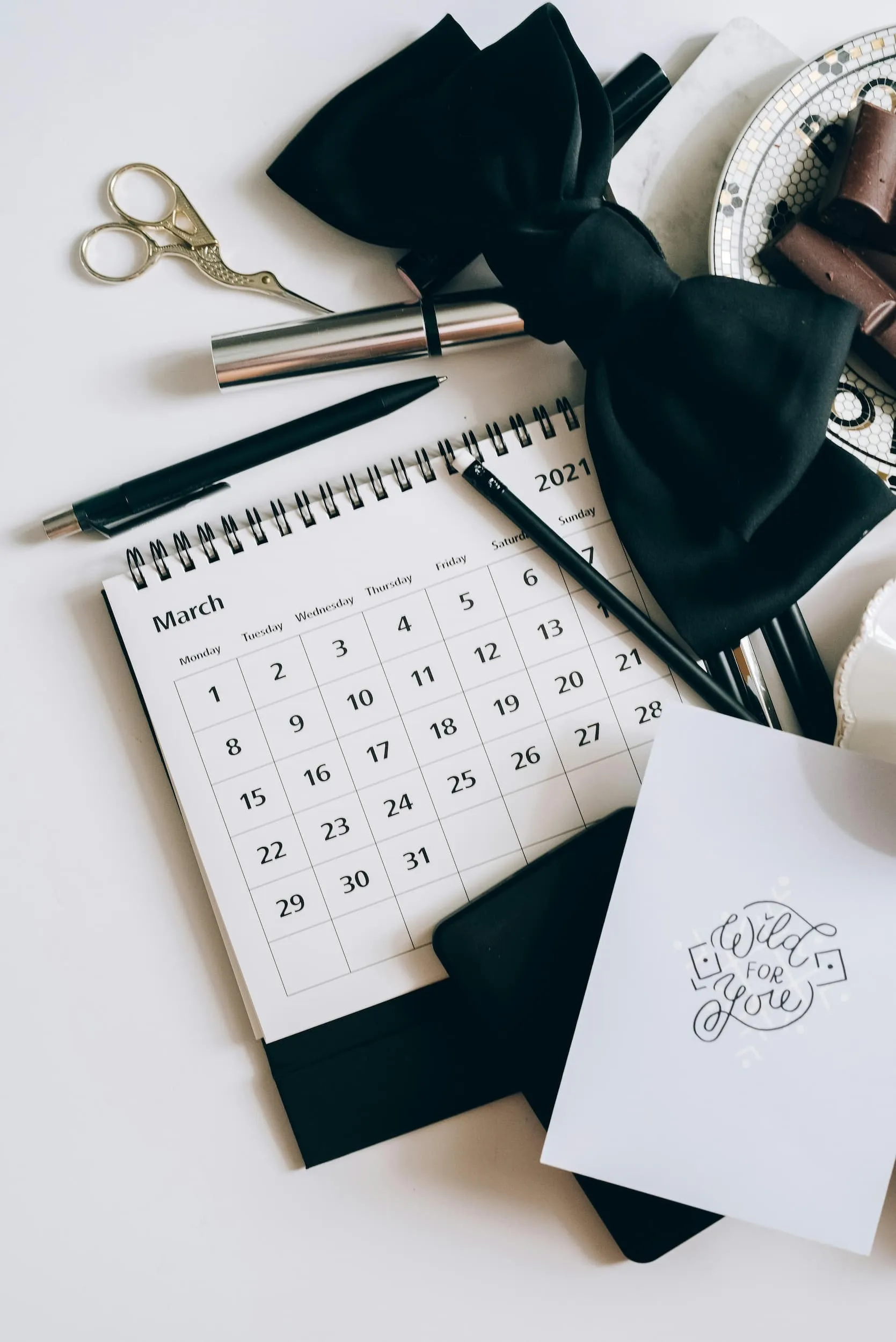 Diverses coses sobre una taula. Tisores, calendari, llapis, paper.